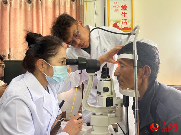王紅英（左）和團隊成員為達熱村村民檢查眼睛。人民網記者 杜燕飛攝